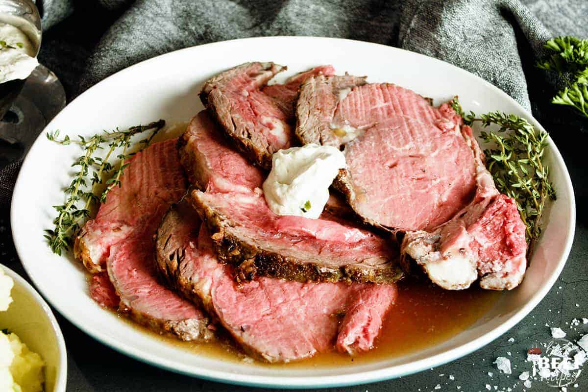 sliced prime rib on a plate served with horseradish sauce