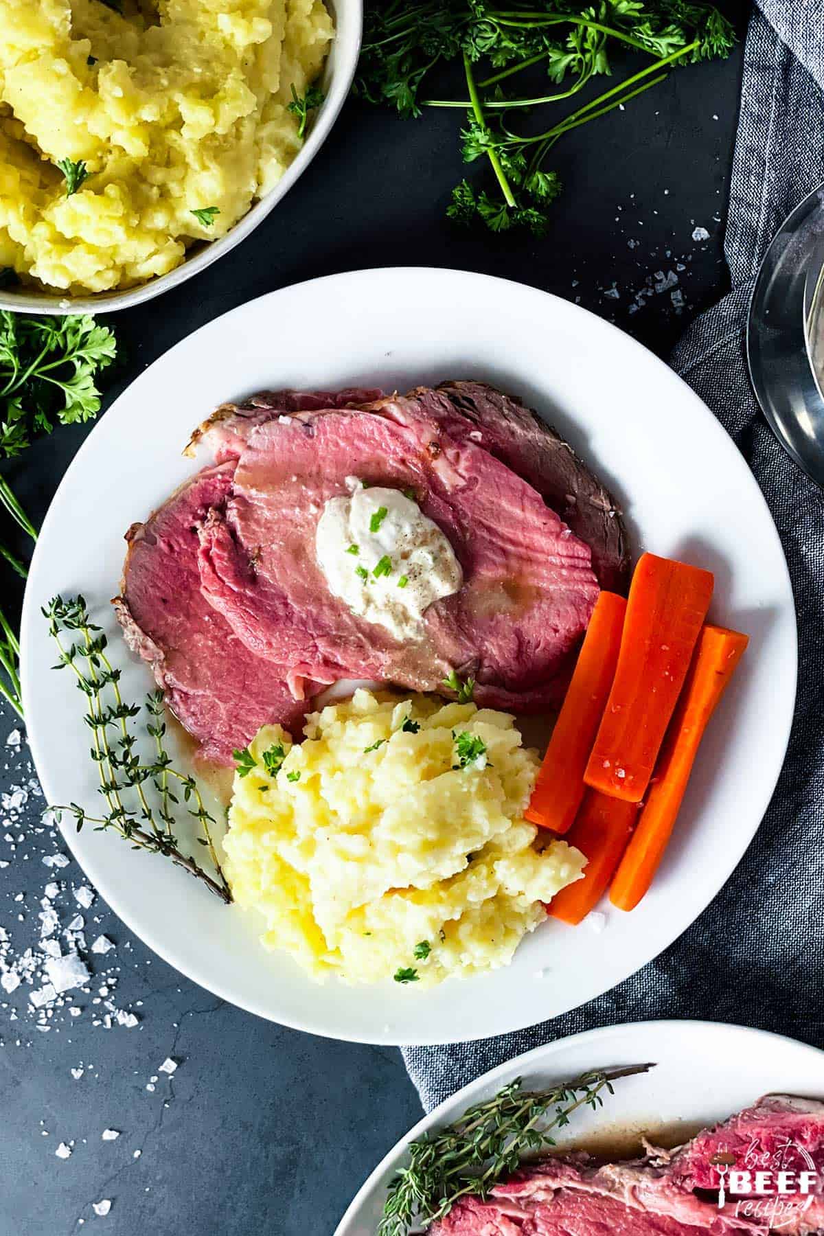 plate of prime rib, mashed potatoes, and carrots, with horseradish sauce on top