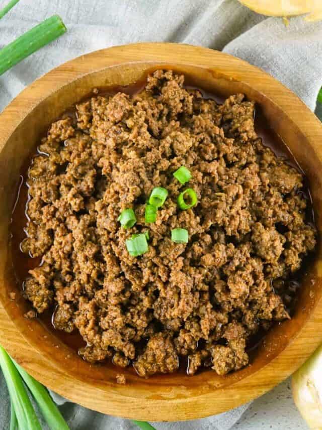 Crockpot taco meat in a wooden bowl with green onions on top