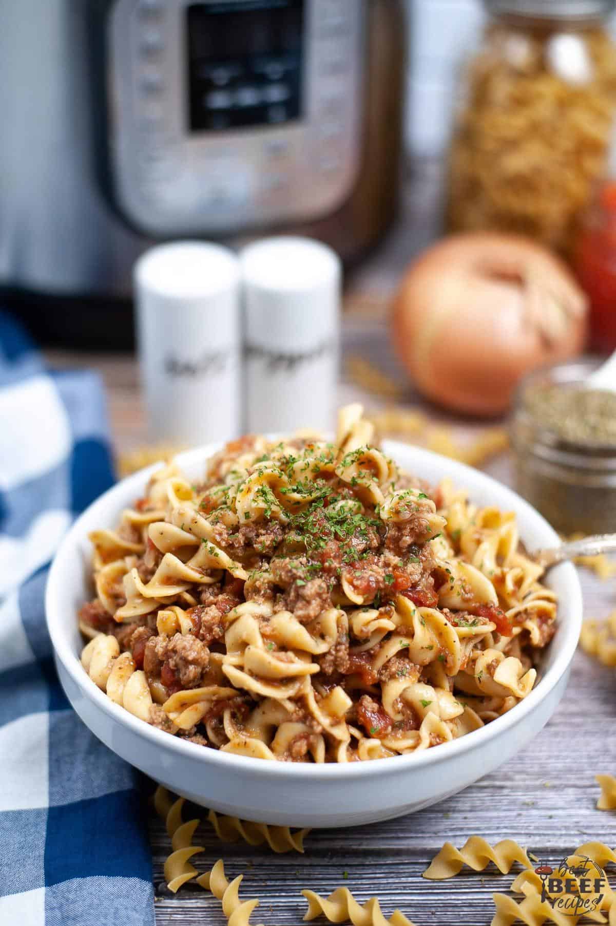 goulash with beef in white bowl next to instant pot
