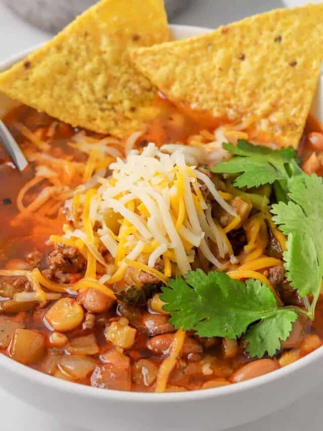 taco soup in a white bowl with tortilla chips and a spoon