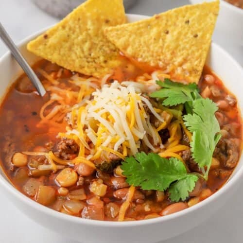 taco soup in a white bowl with tortilla chips and a spoon