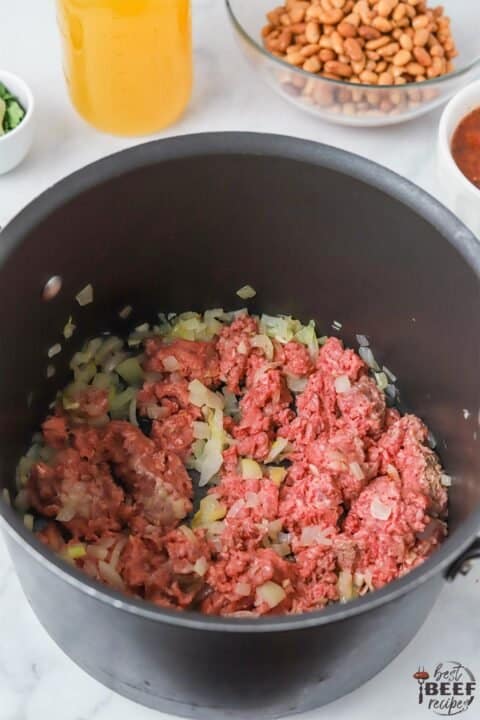 Adding beef to a pot to cook
