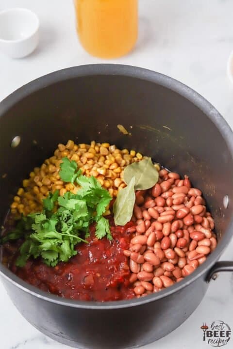 beans, corn, and herbs added to the soup pot
