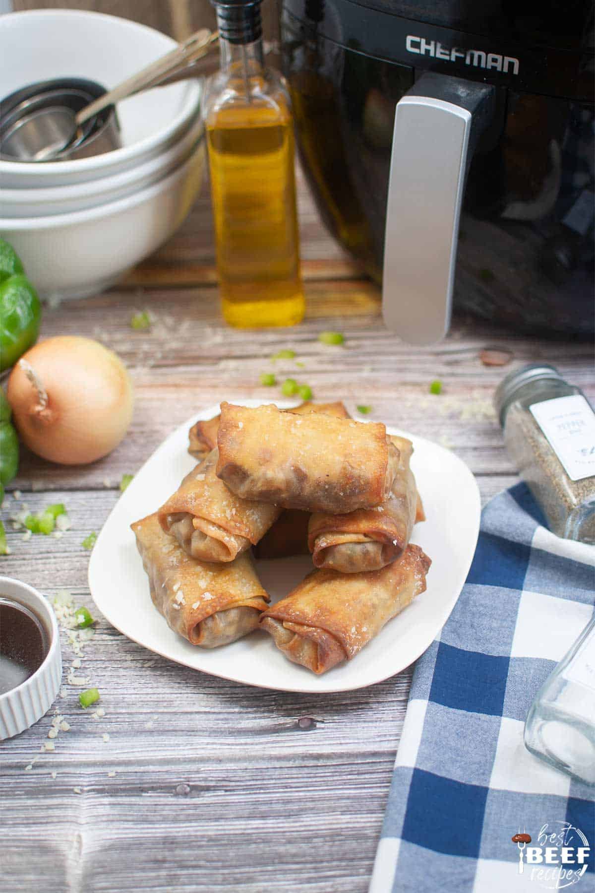 egg rolls on a plate next to air fryer