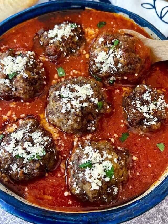 meatballs in a bowl of sauce with parmesan on top