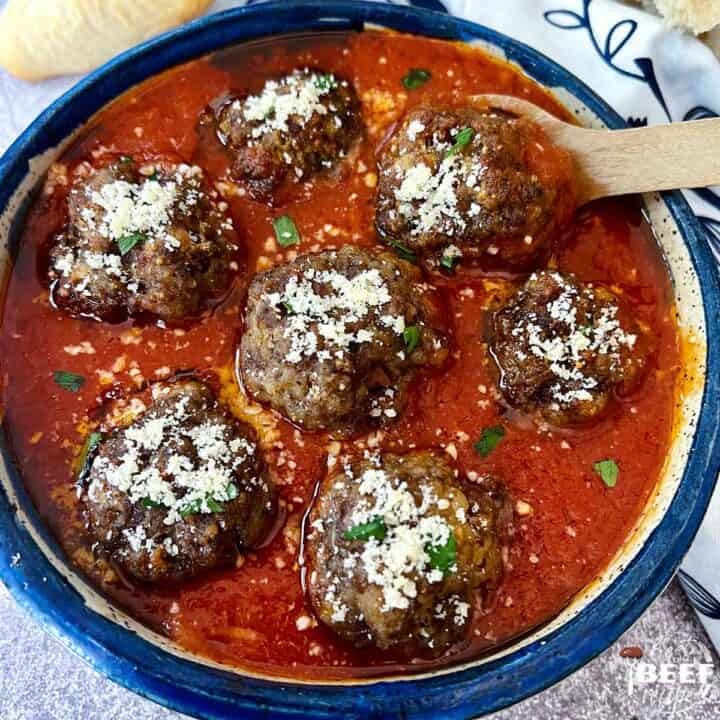 meatballs in a bowl of sauce with parmesan on top