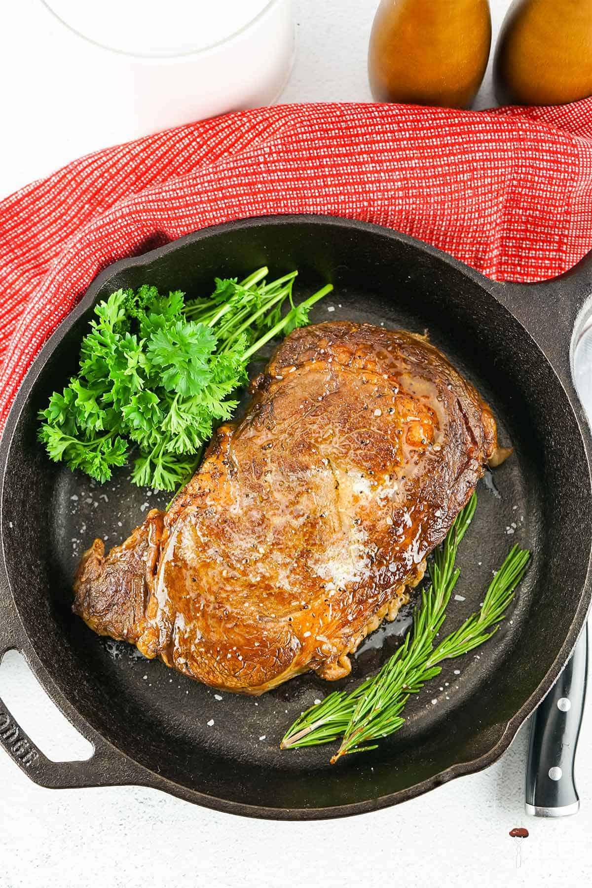 sous vide steak in a cast iron pan with fresh herbs