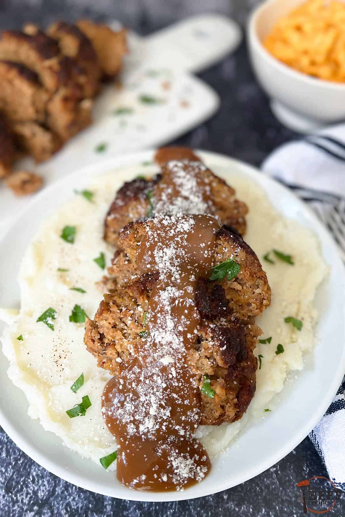 air fryer meatloaf with gravy and parmesan cheese over a bed of mashed potatoes