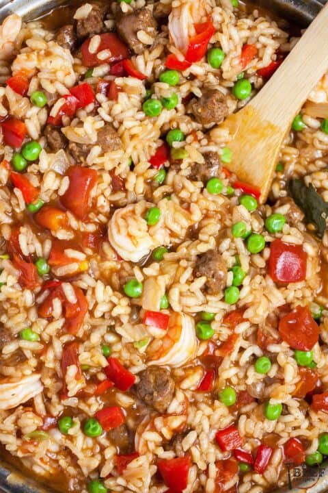 adding shrimp and beef to paella skillet