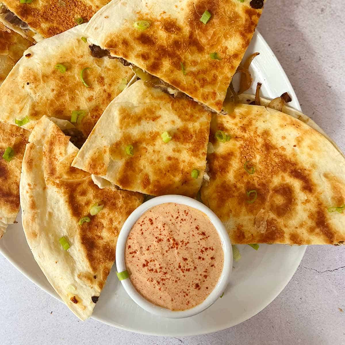 quesadilla sauce in a bowl with beef quesadillas on a plate