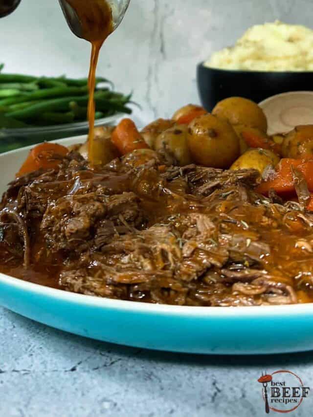 pouring gravy over instant pot pot roast on a plate with carrots and potatoes, in front of a bowl of green beans and mashed potatoes