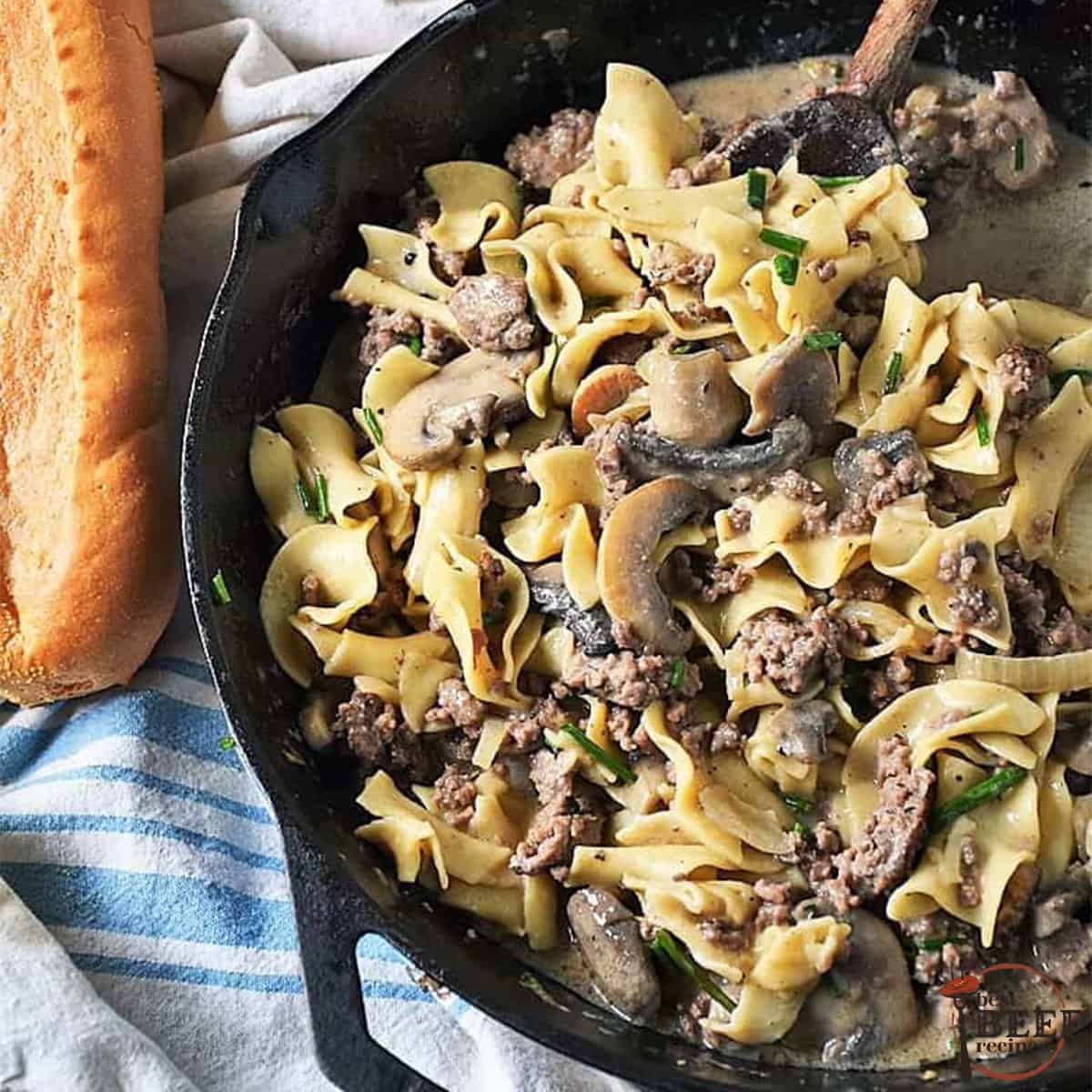 ground beef stroganoff in a black skillet next to bread