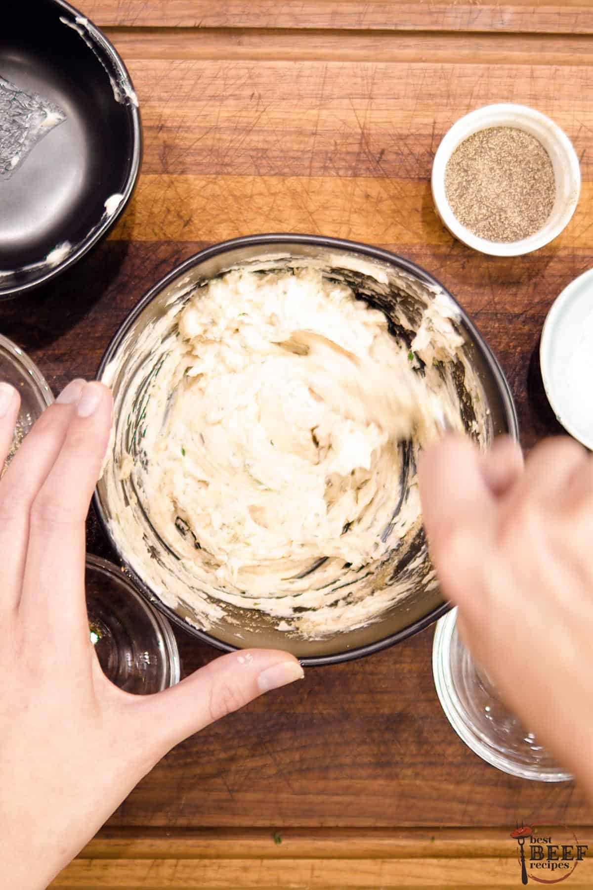 Close-up of a bowl of butter rub being mixed with a fork by hands