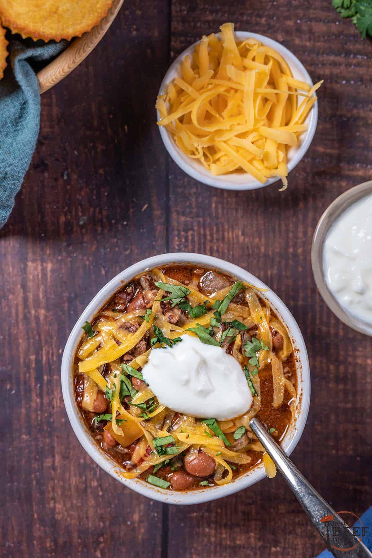 bowl of beef chili topped with cheese and sour cream