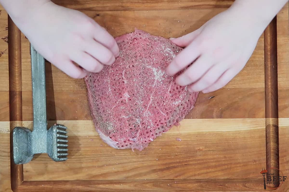 Seasoned tenderized steak on a cutting board