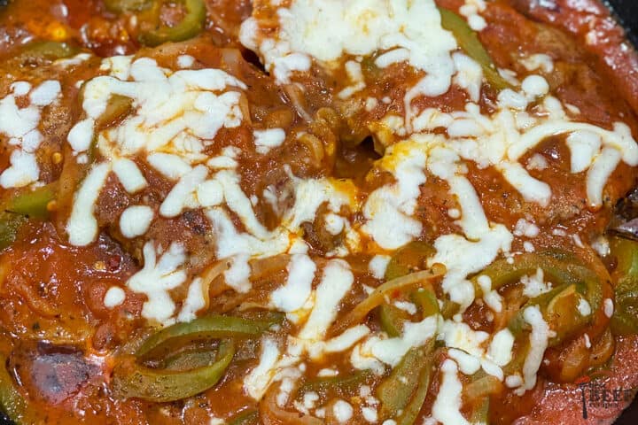 Close up of steak pizzaiola in the skillet topped with cheese