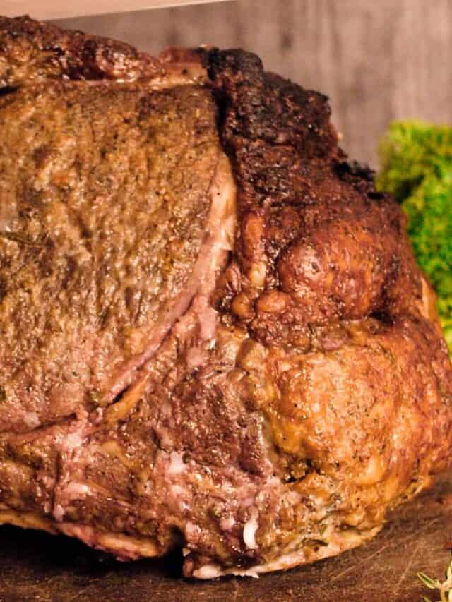 A roasted prime rib on a cutting board with lettuce