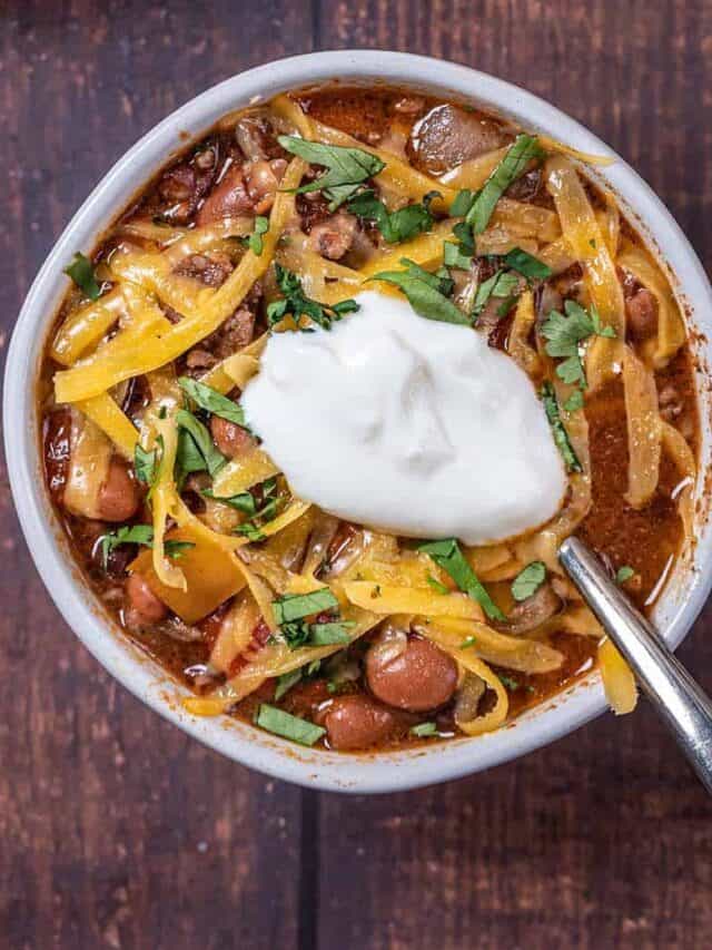 bowl of beef chili topped with cheese and sour cream