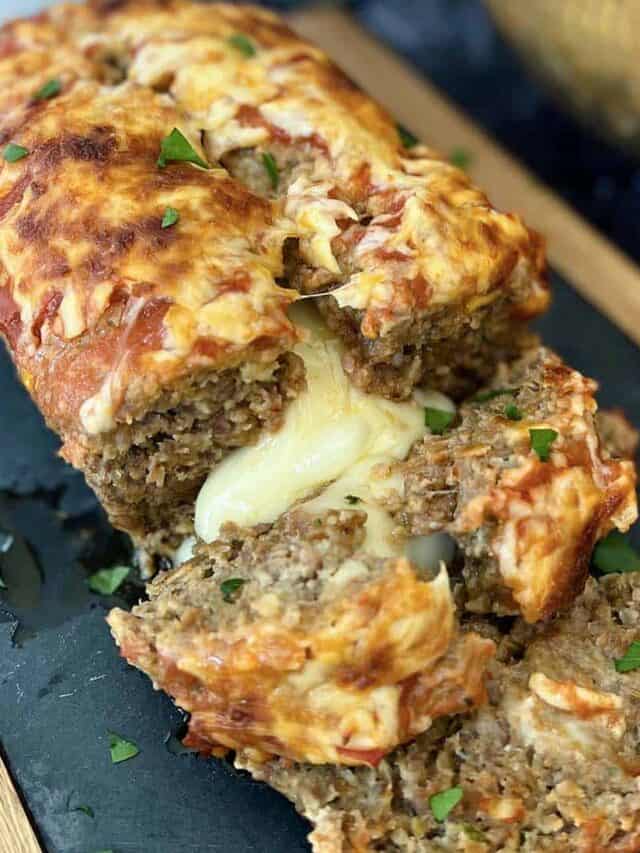italian meatloaf on a serving board with gooey mozzarella cheese at the center