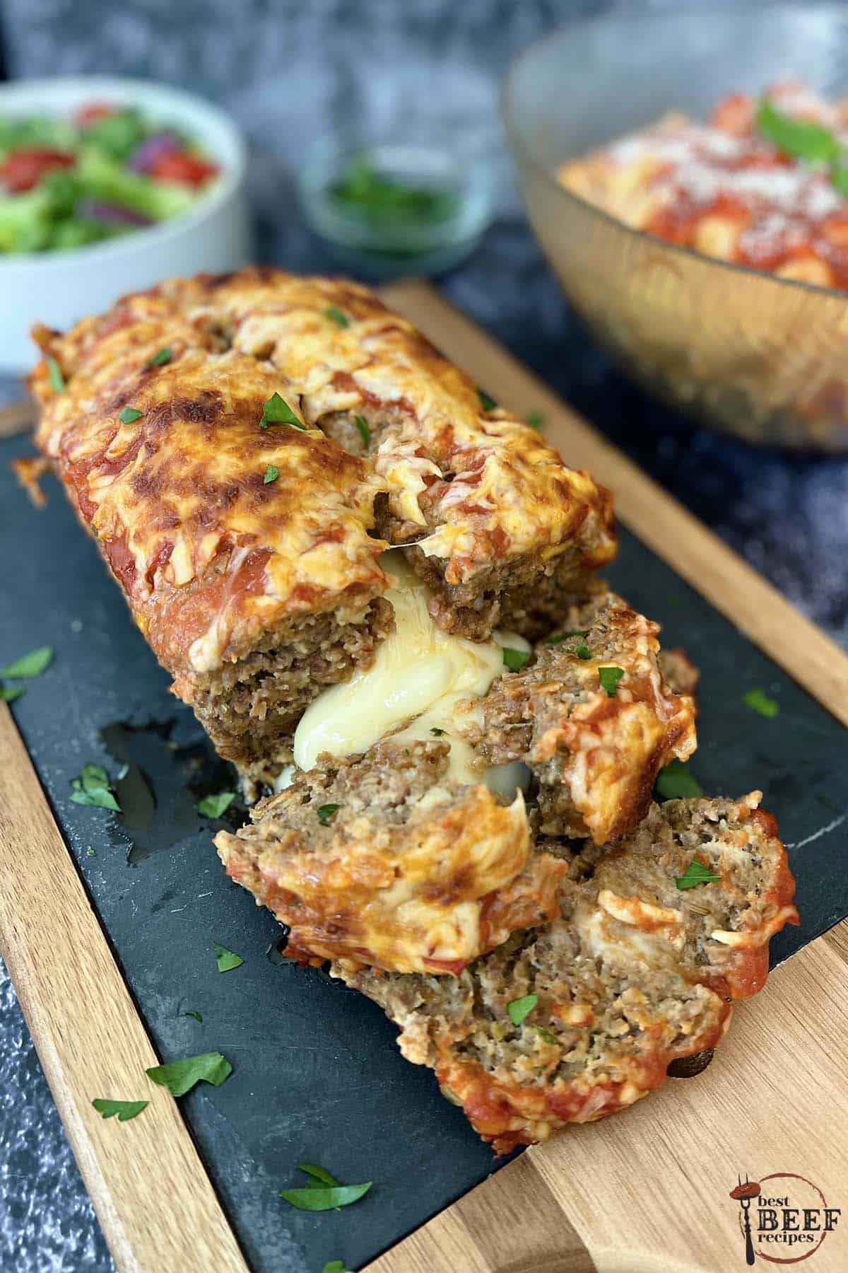 italian meatloaf on a serving board with gooey mozzarella cheese at the center