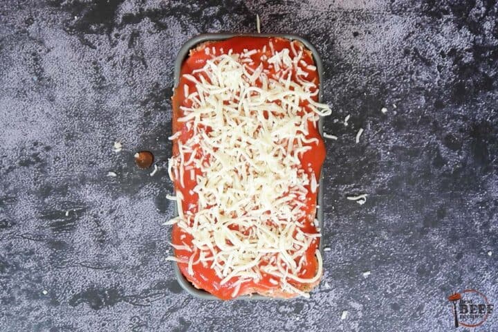 italian meatloaf covered with tomato sauce and cheese ready to bake