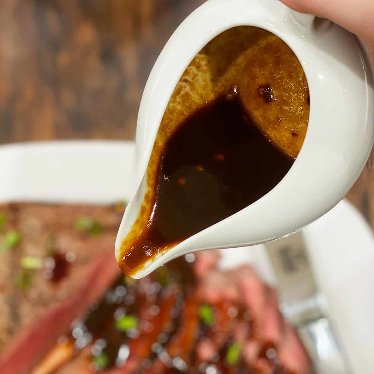 close up of london broil marinade sauce in a white dish ready to pour over steak