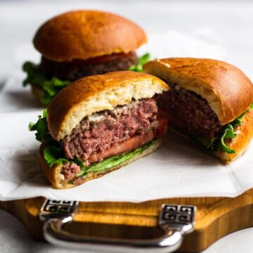 Air Fryer burger with traditional burger toppings cut in half with the inside showing