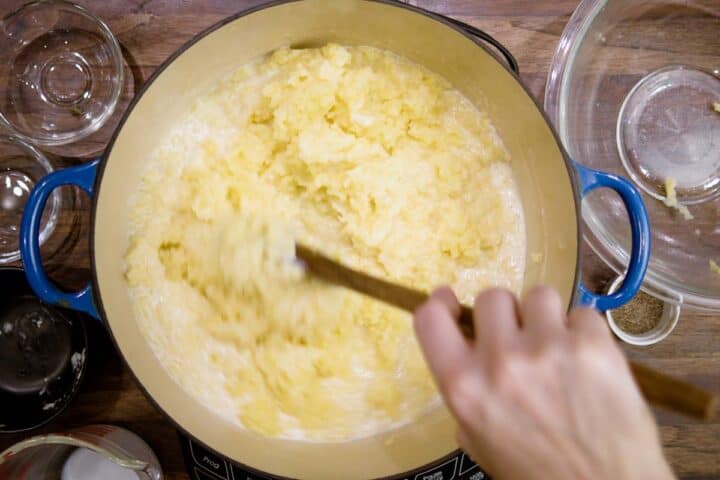 Slowly stirring mashed potatoes with milk mixture