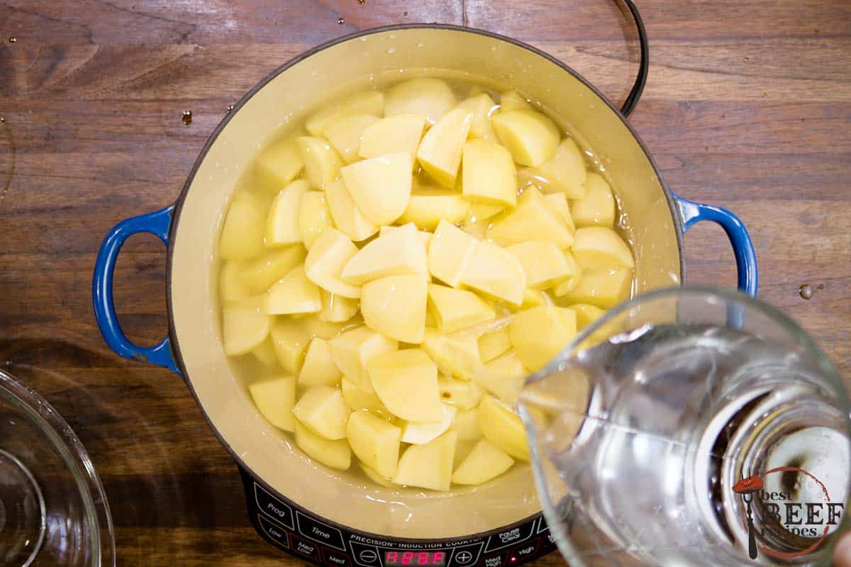 adding water to a pot with cut potatoes