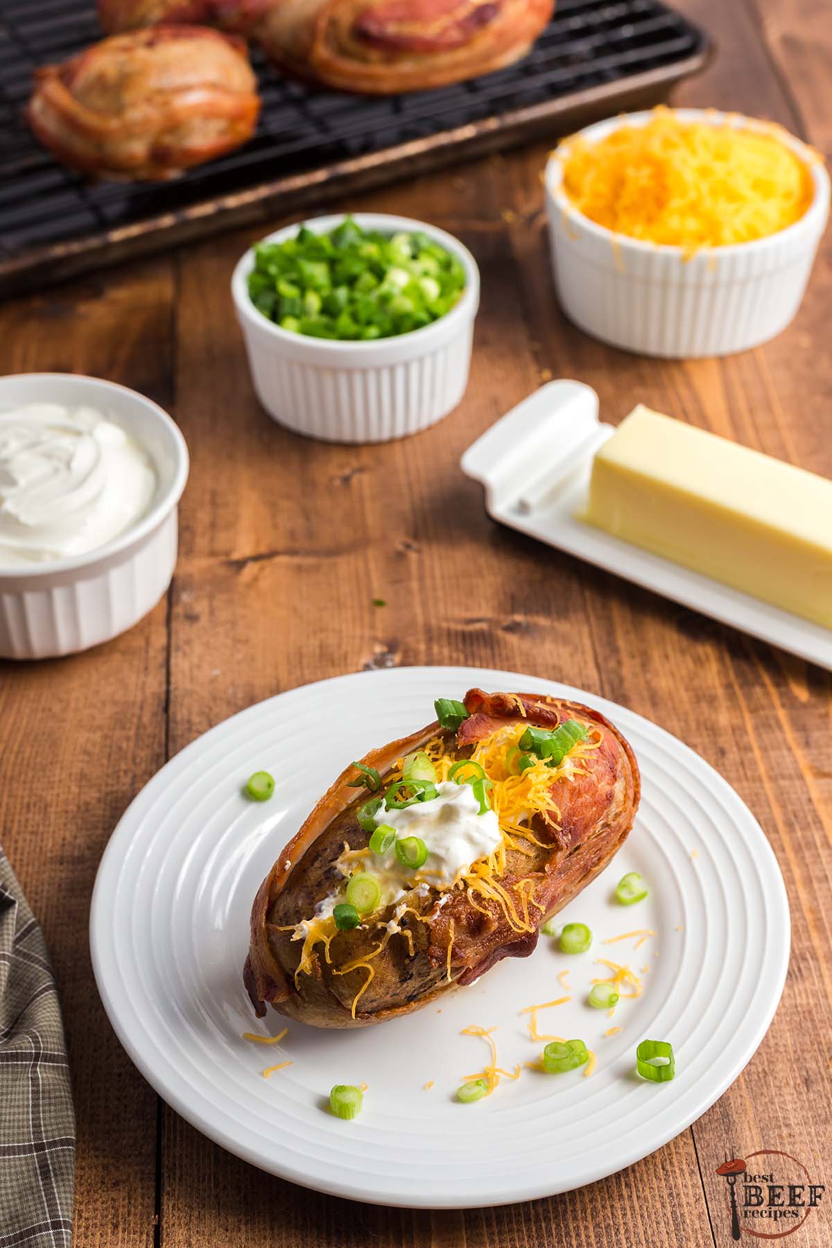steakhouse baked potato on a plate with green onions, sour cream and cheese