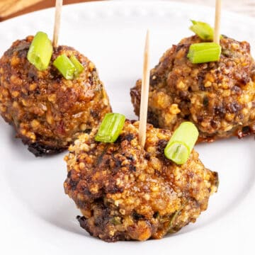 a white plate with three hoisin meatballs stuck with toothpicks