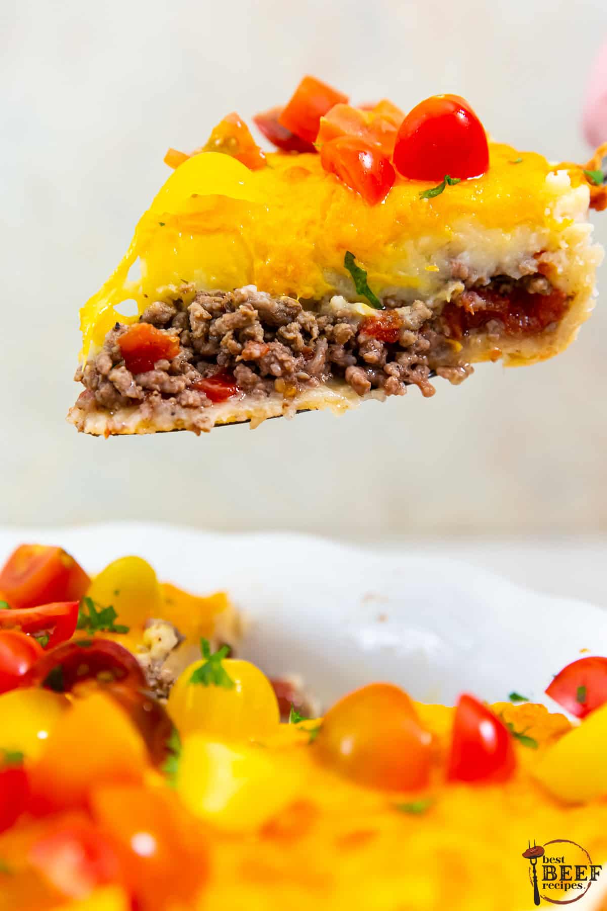 a slice of cheeseburger pie being lifted out of a pie dish with a pie slicer