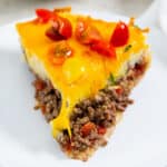 a front view of a slice of cheeseburger pie on a white plate