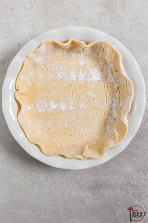 a pie crust in a pie dish with holes poked in the bottom of the crust