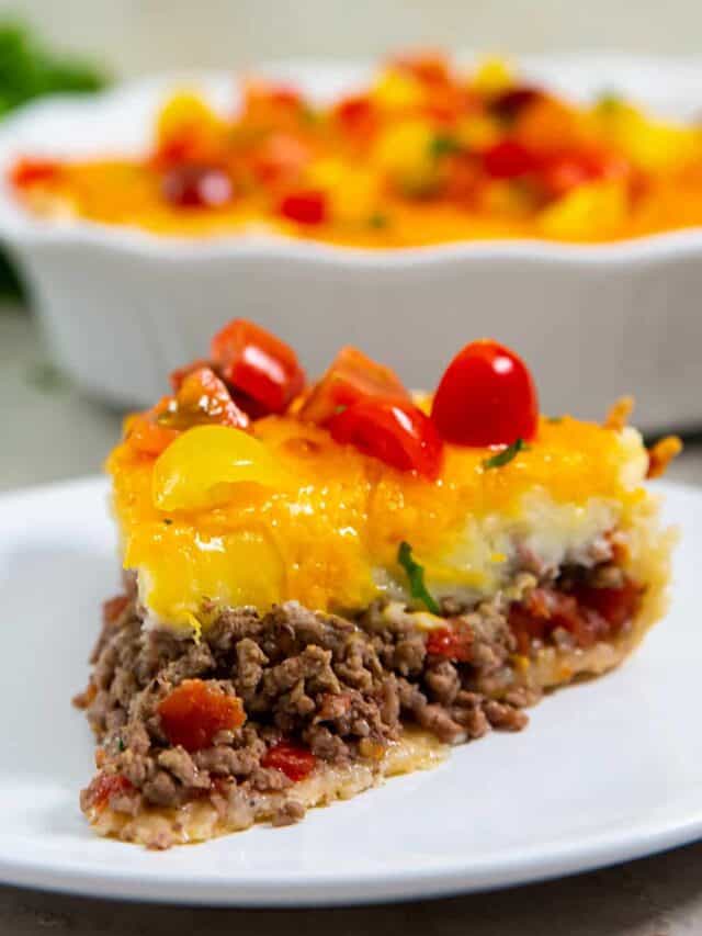 a closeup view of cheeseburger pie on a plate with a dish of pie in the back