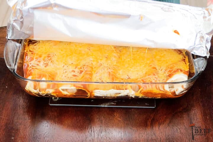 ground beef enchiladas in a baking dish with tin foil overtop