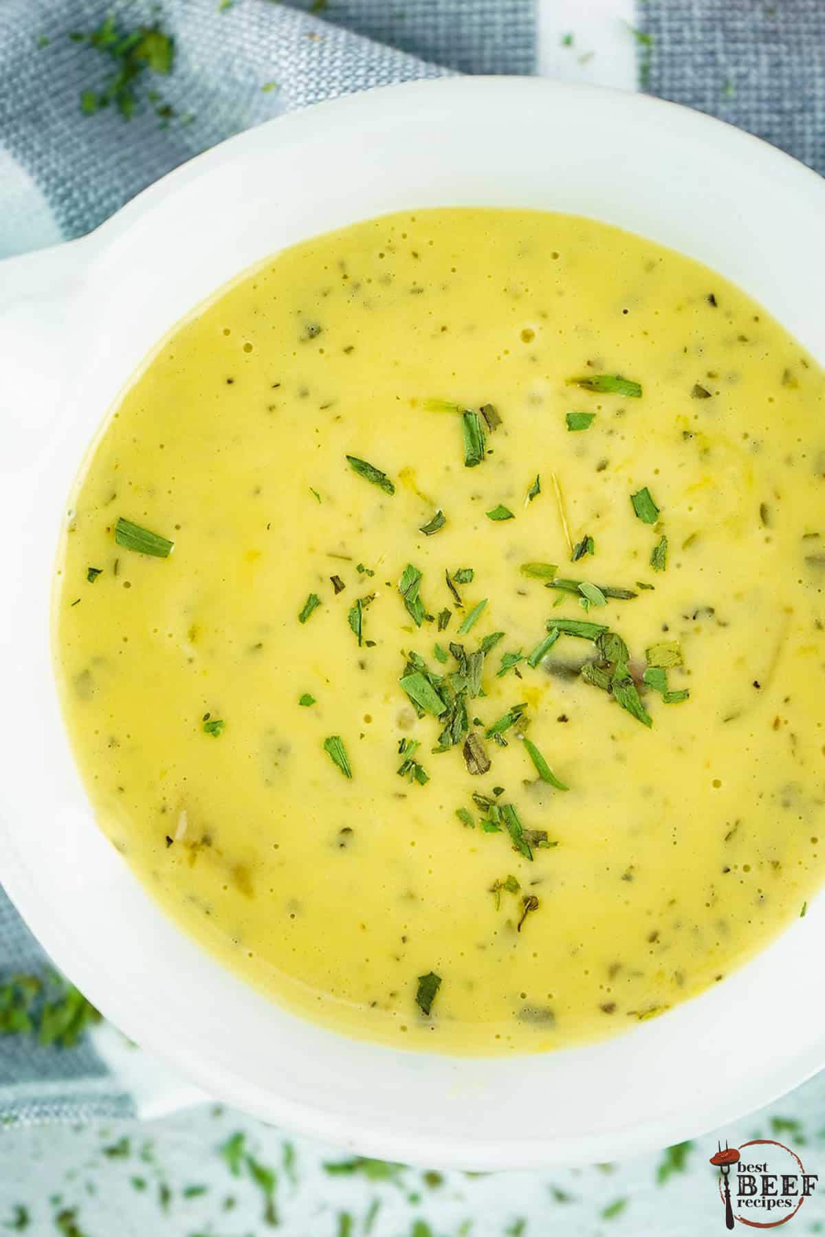 a top down view of a bowl of bearnaise sauce with sprinkled herbs