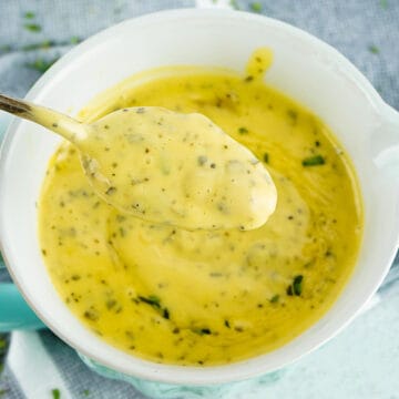 a spoonfull of thick bearnaise sauce over a bowl of bearnaise