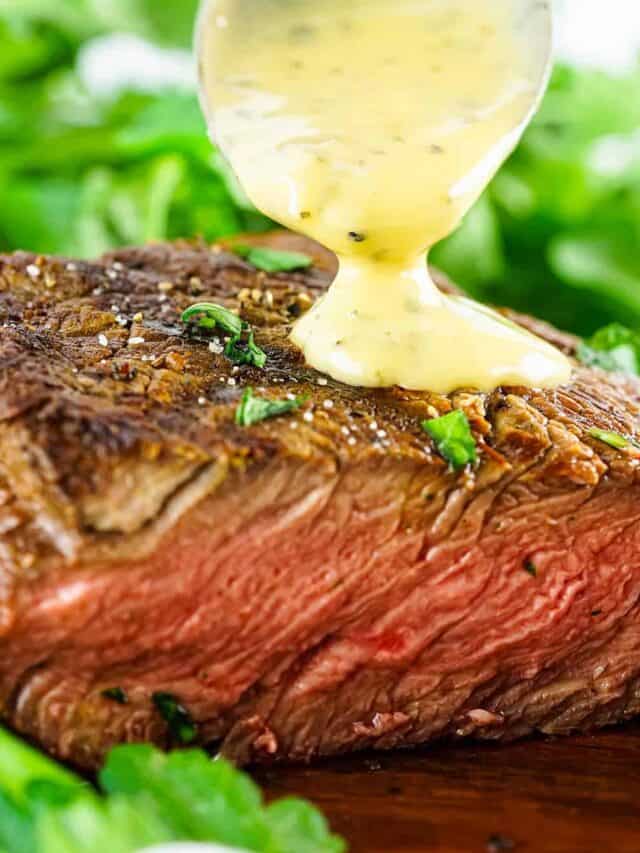 bearnaise sauce being poured off a spoon on to a slice of steak