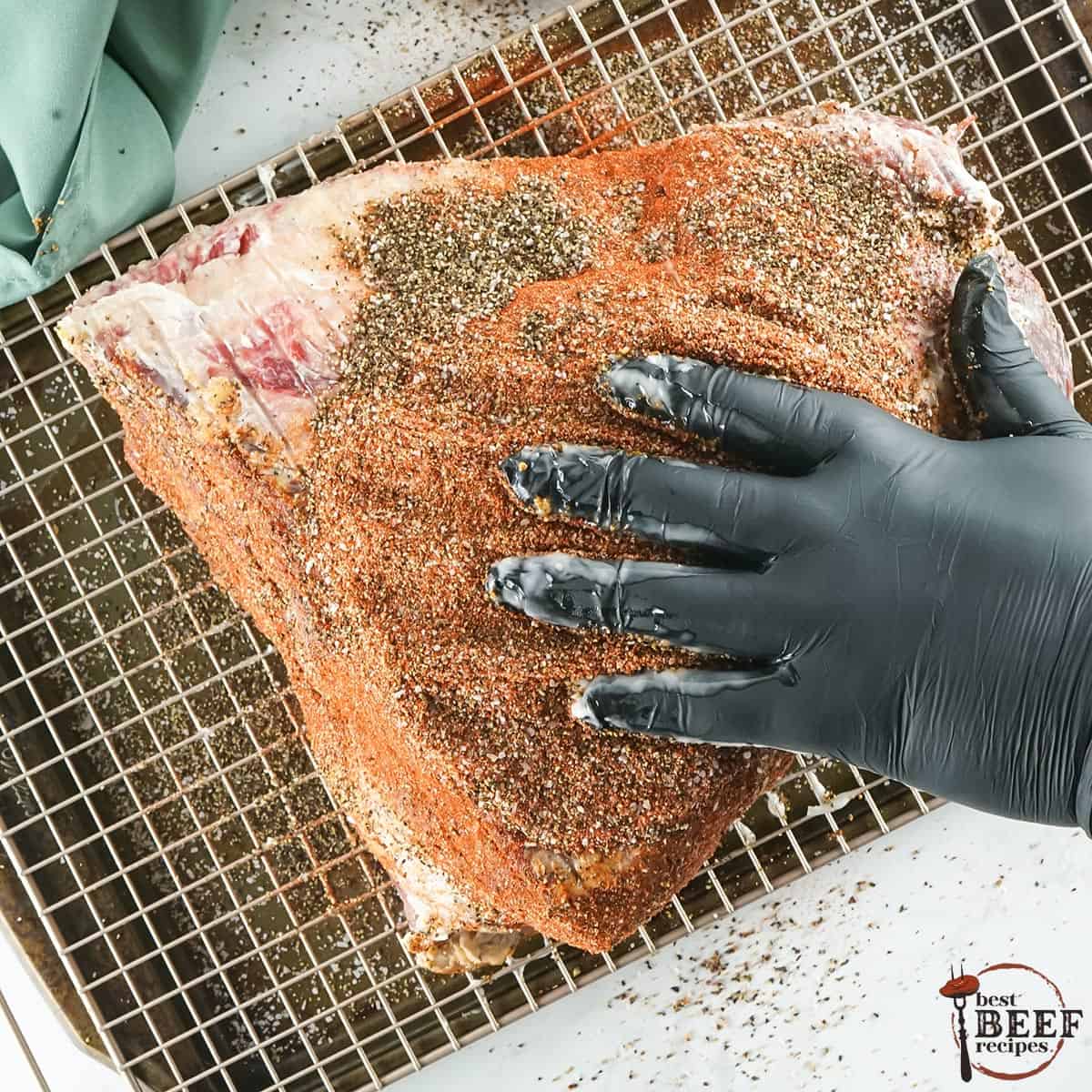 patting down a brisket with bbq rub