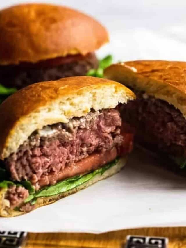 two burgers on parchment paper, one cut open to show the pink inner meat