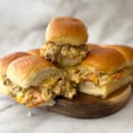 philly cheesesteak sliders stacked on a wood cutting board