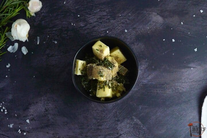 butter with herbs and seasonings in a black bowl, unmixed
