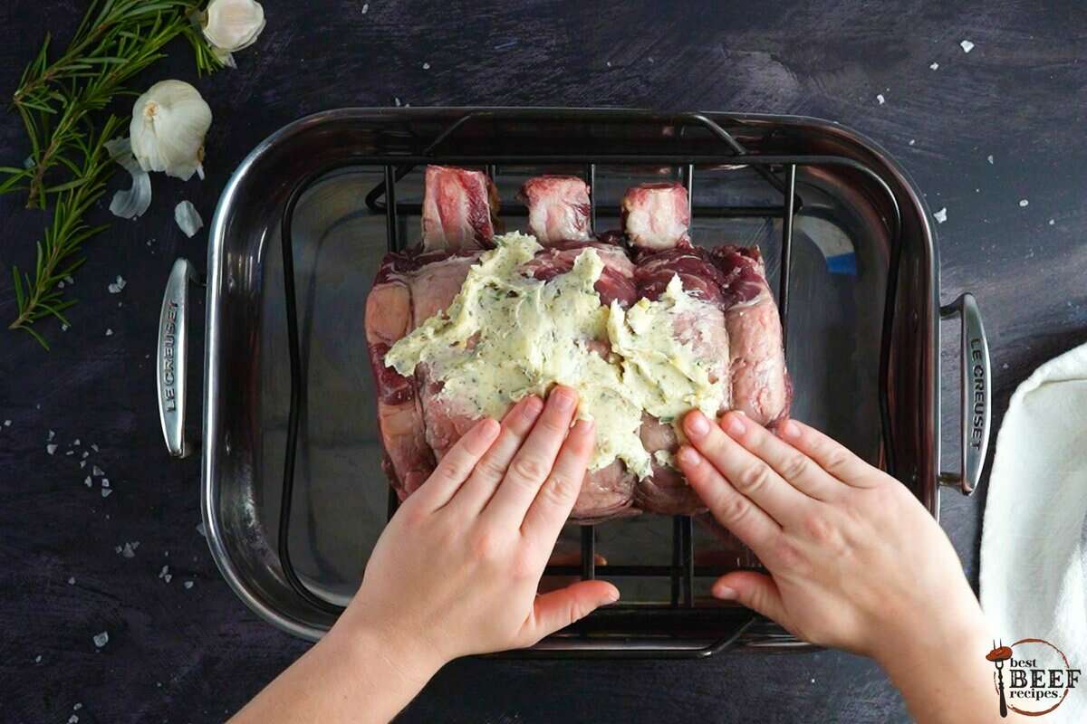 rubbing prime rib with butter rub using both hands