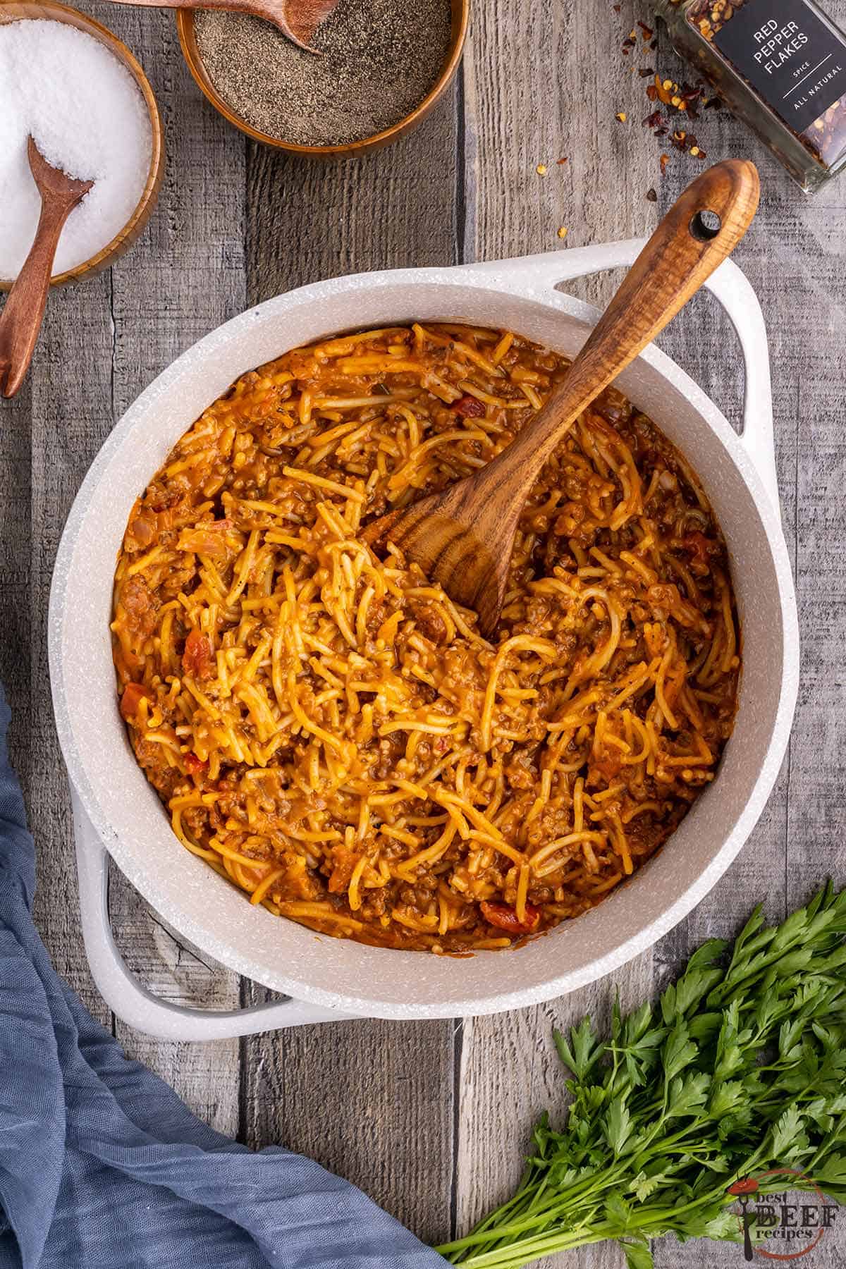 a big pot of one pot spaghetti with a wooden serving spoon
