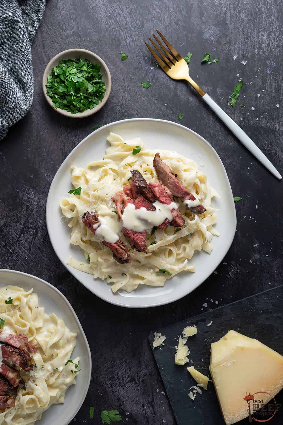 steak Alfredo on a white plate with parsley on the side