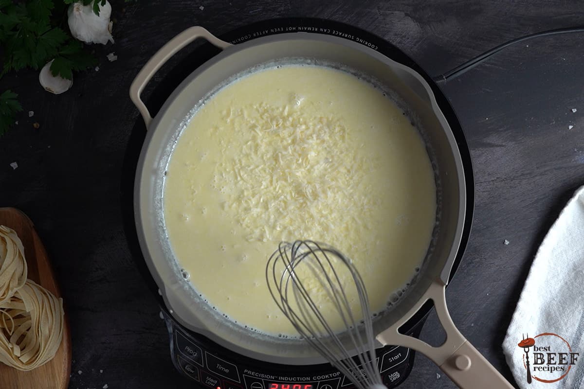 adding parmesan cheese to a skillet for Alfredo
