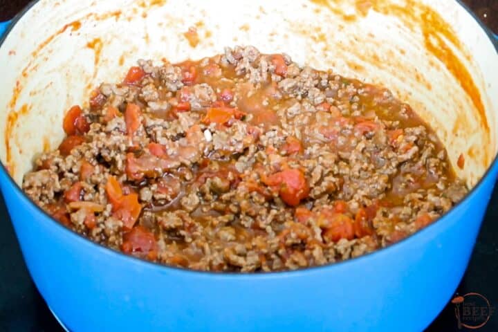 meat added to tomato sauce in a large pot to simmer