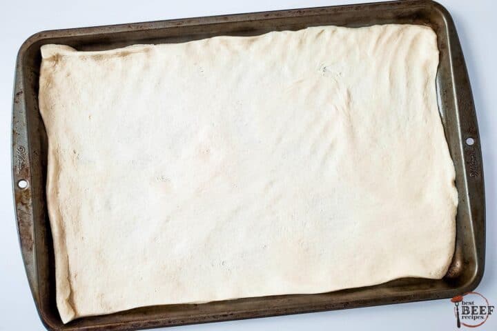 pizza dough rolled out on a sheet pan